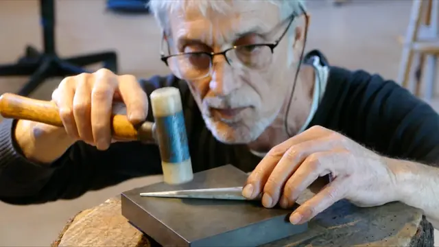 Xavier Domènech formt mit dem Hammer einen Metallstab auf einem Stahlblock
